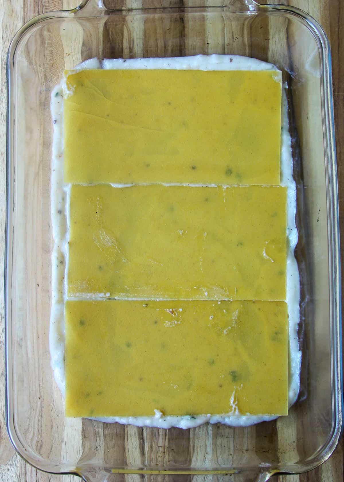 A layer of uncooked lasagna noodles in the pan.