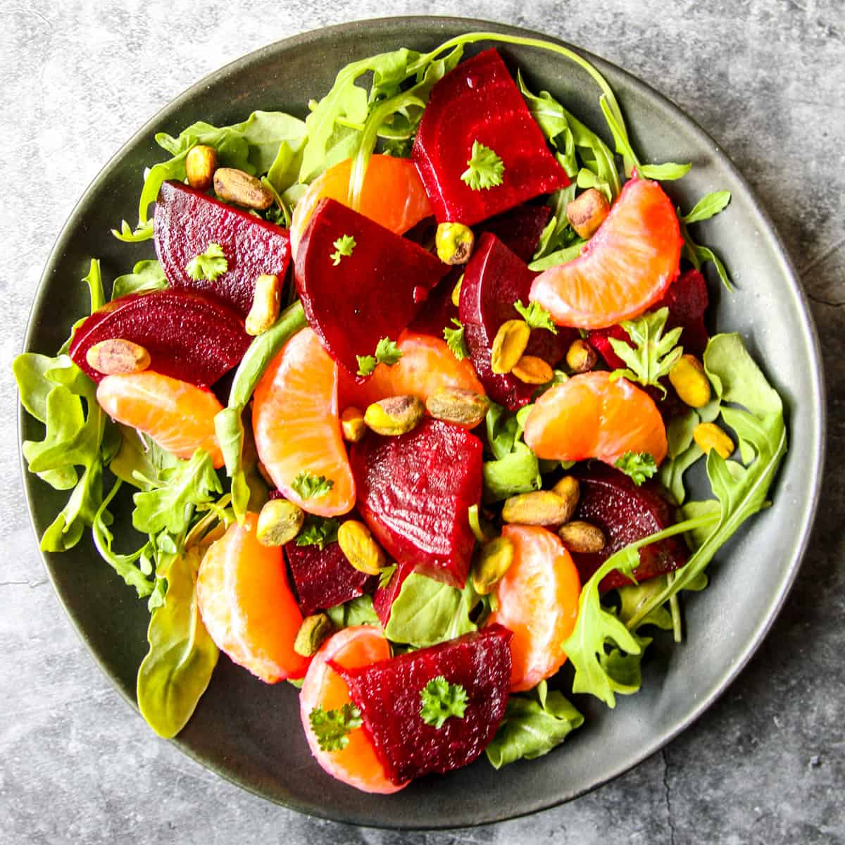 Colorful beet and orange salad on a black plate.