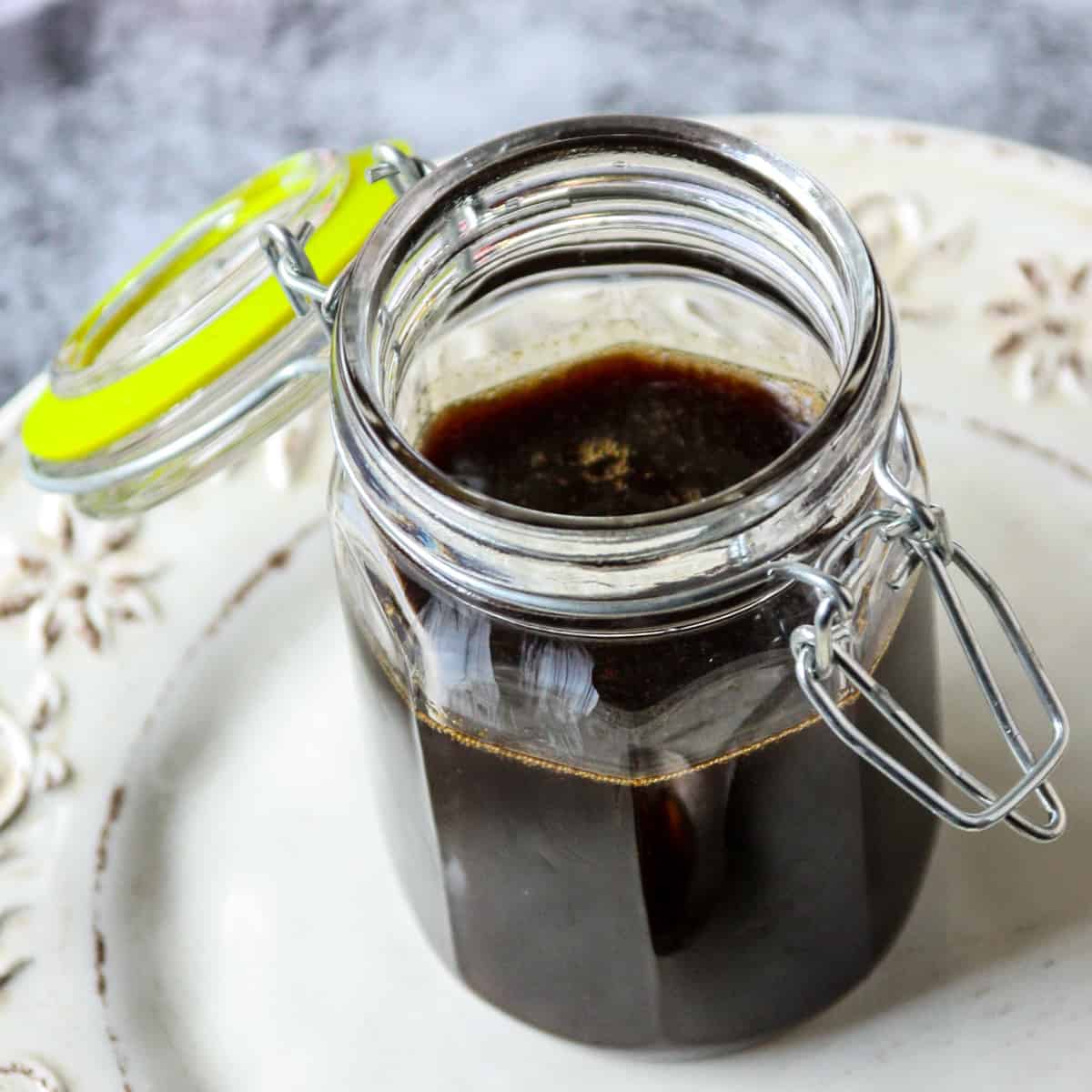 Gingerbread syrup in a glass jar, on a white plate.