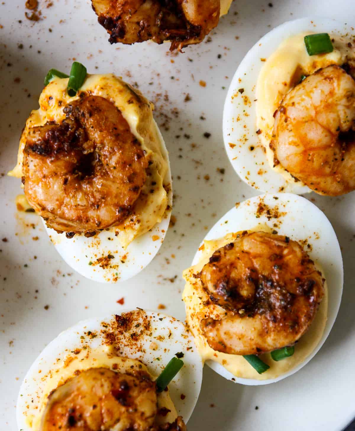 Four Cajun shrimp deviled eggs garnished with green onion slices.