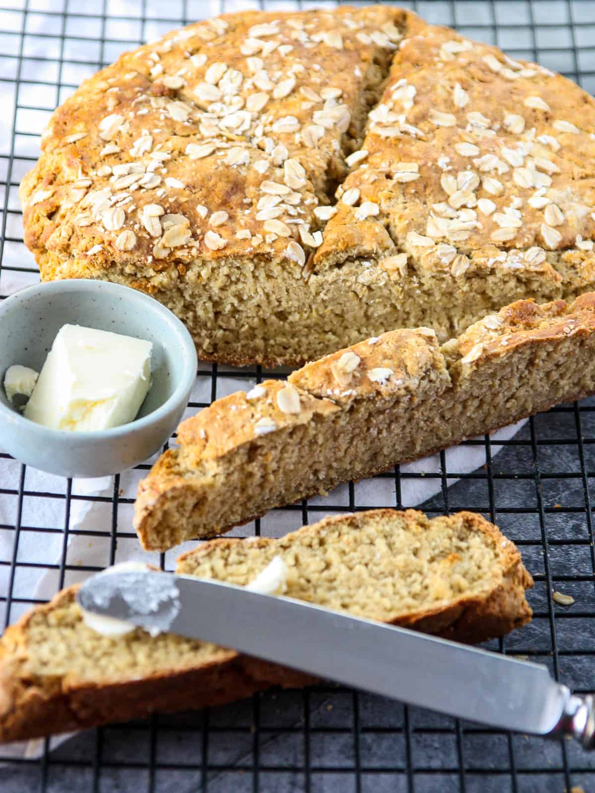 Butter being spread on a slice of soda bread with a knife.