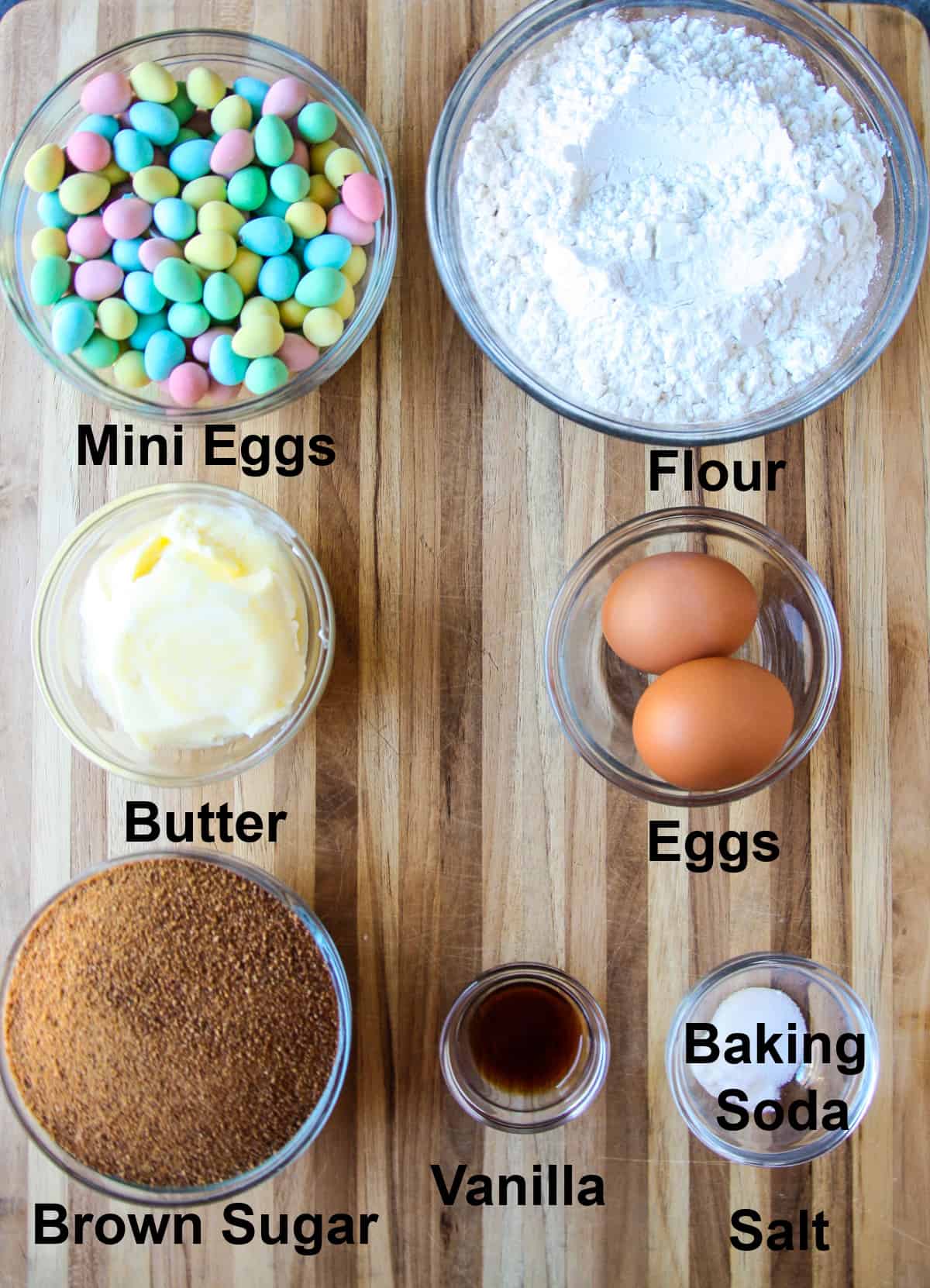 The recipe ingredients in glass bowls on a wood cutting board.