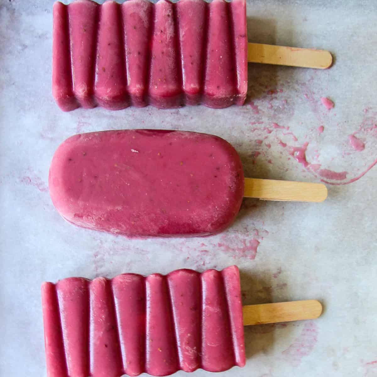 Three strawberry popsicles.