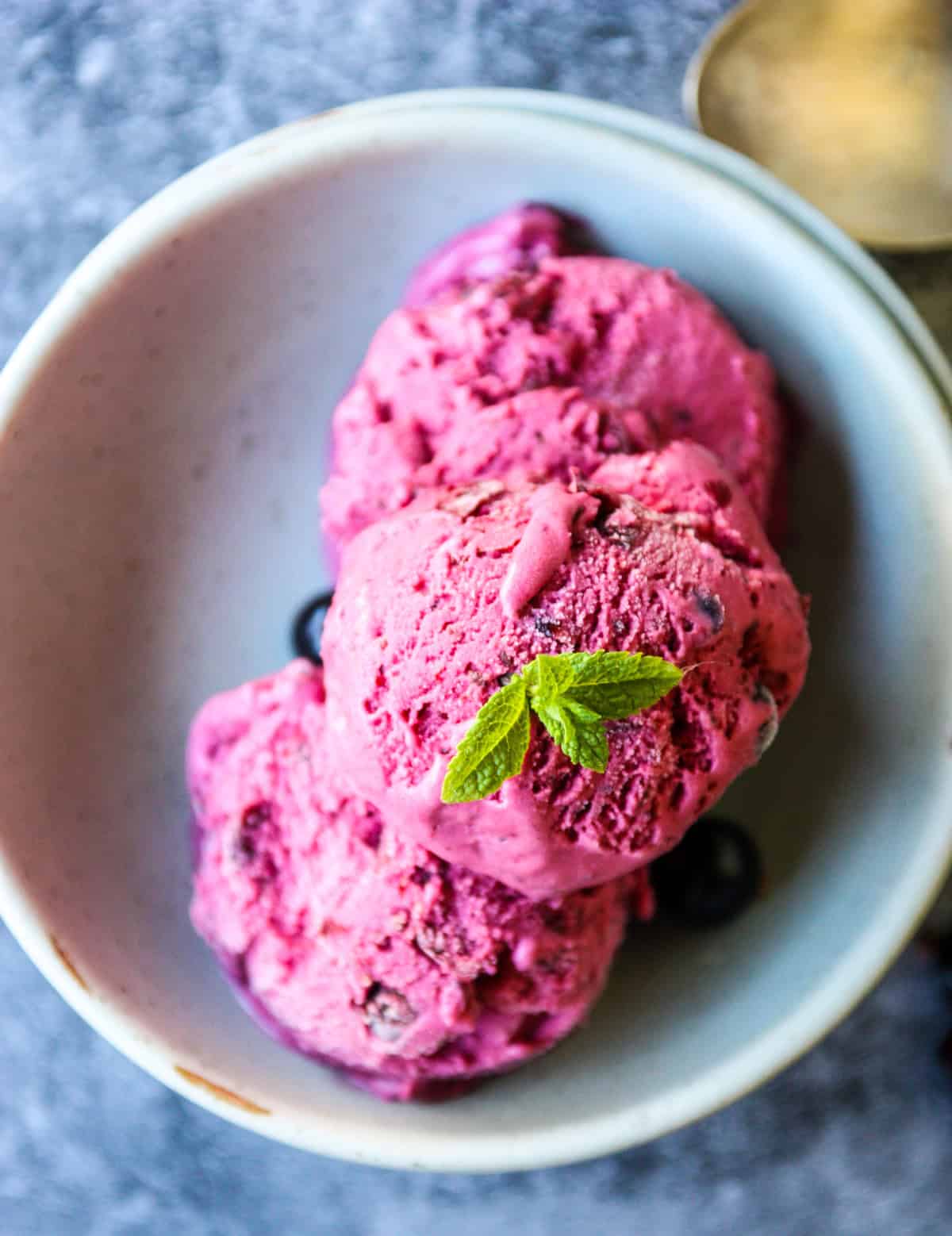 Bright pink scoops of black currant ice cream in a light green bowl.
