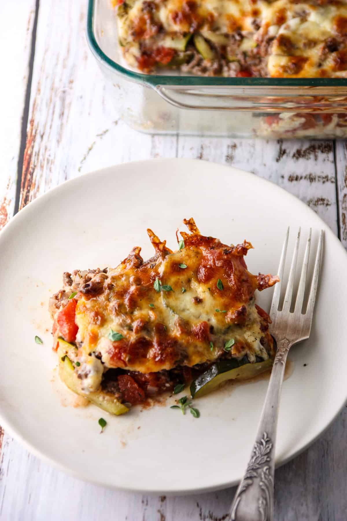 A slice of ground beef zucchini casserole on a white plate.