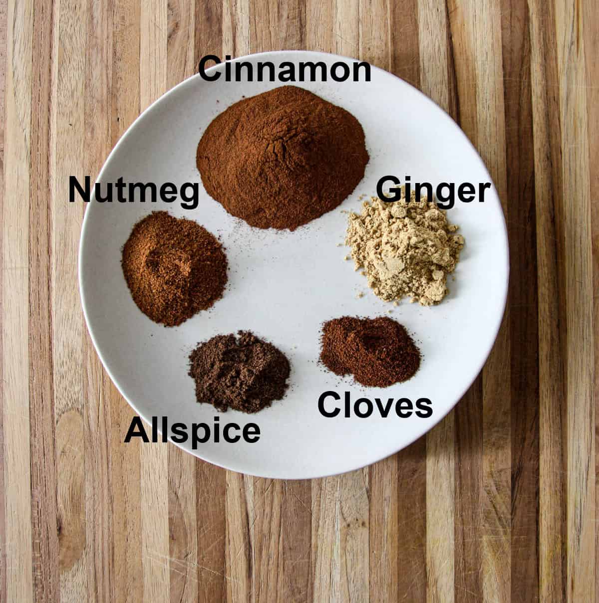 The five spice ingredients for making pumpkin spice on a white plate.