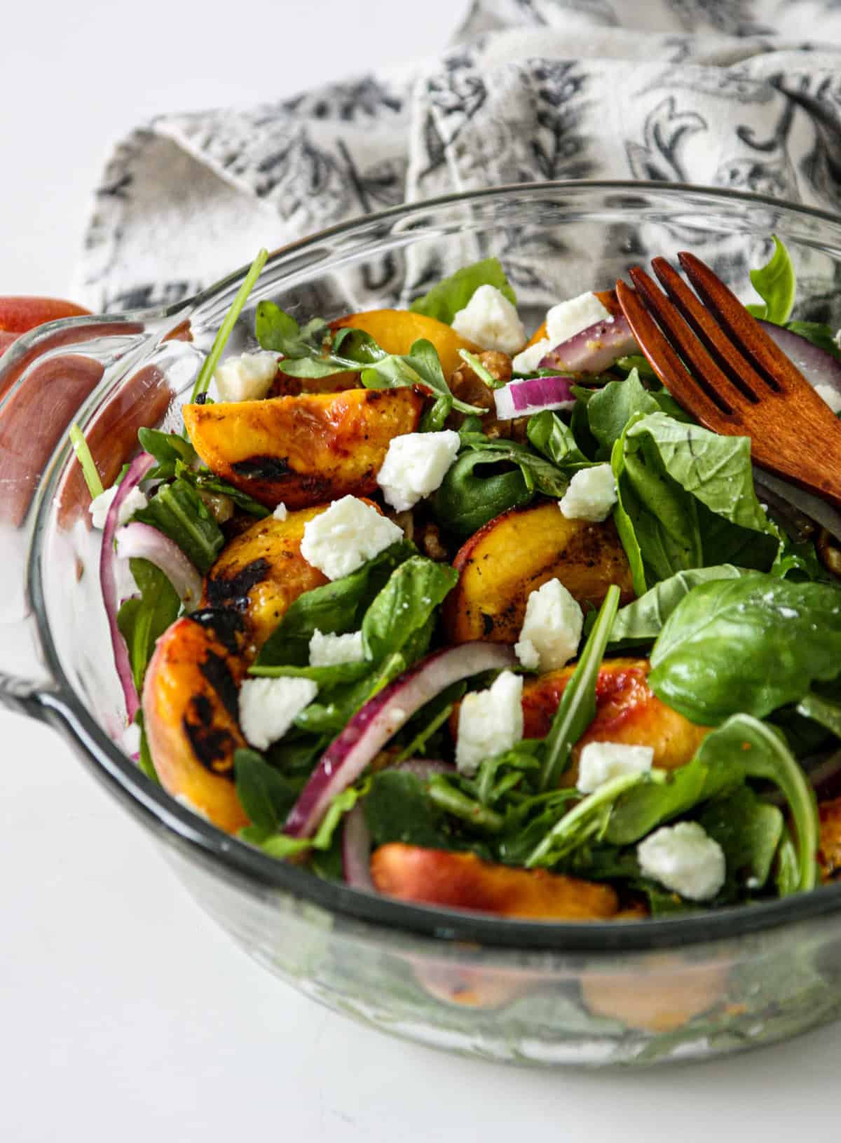 A close up of grilled peach salad with sprinkles of feta cheese.